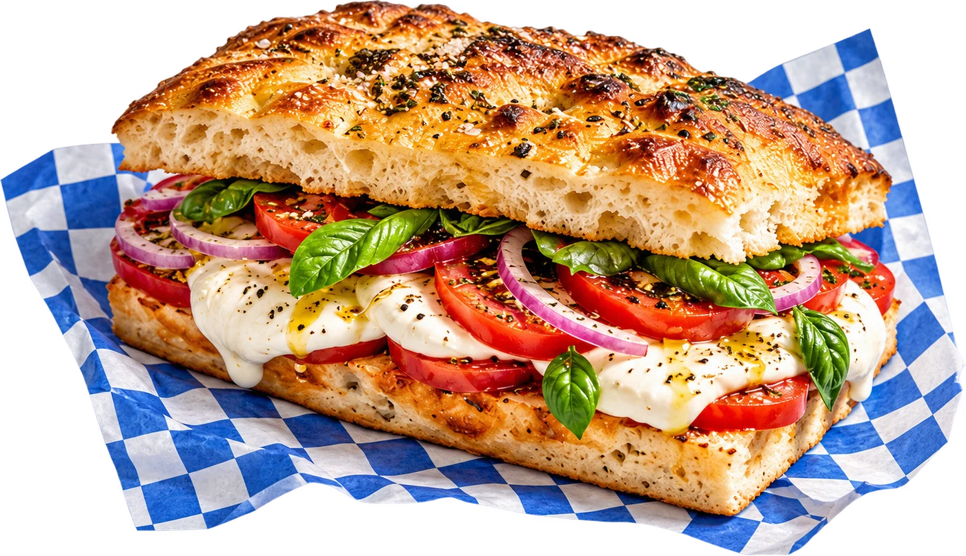 Toasted focaccia filled with mozzarella, tomatoes, greens, and pesto on blue checked deli paper.